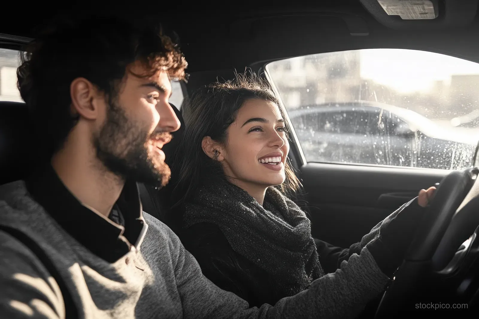 Smiling parents driving a car on a sunny road while children ride in the backseat together.