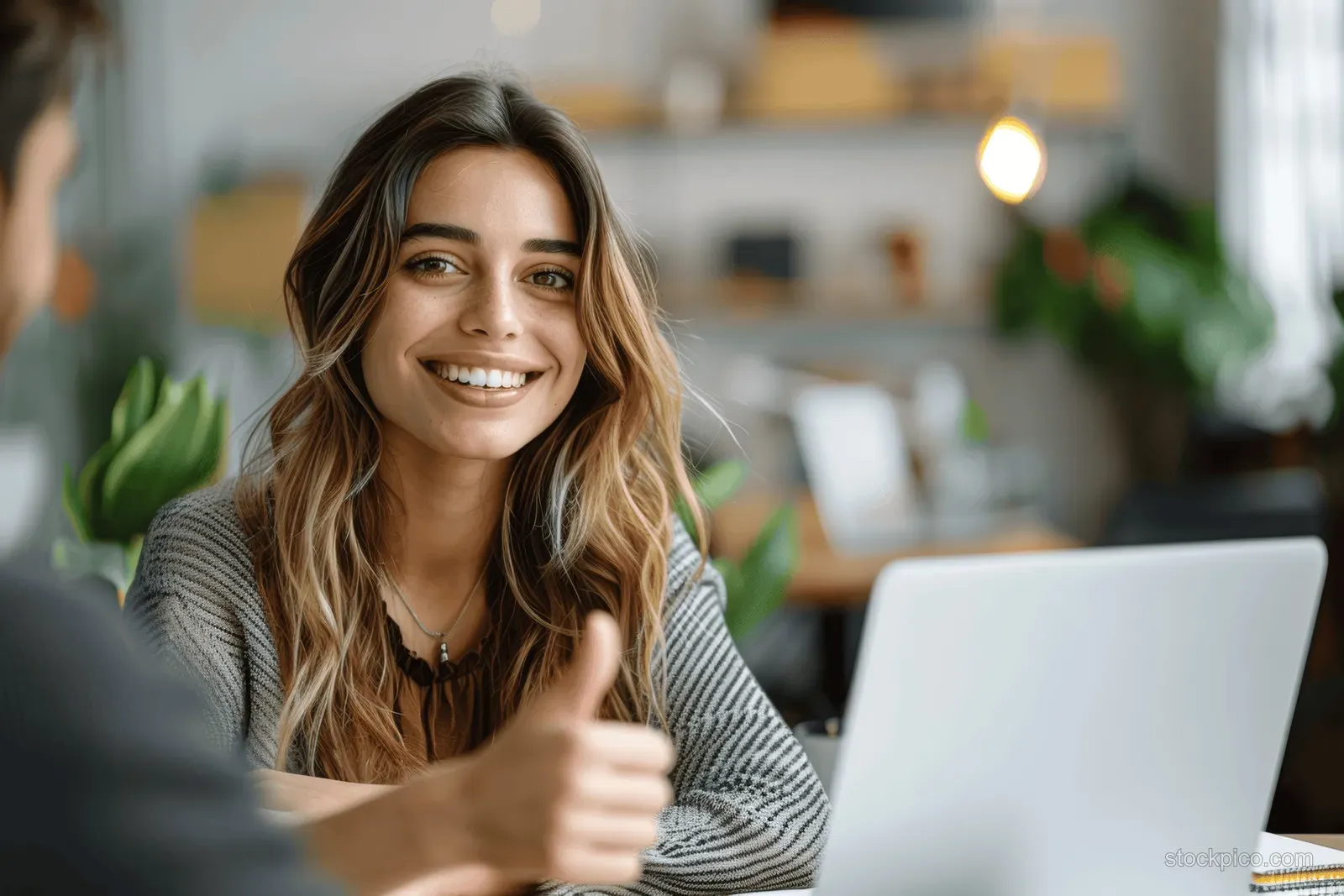 A cheerful young businesswoman engages in a video call, discussing finance and strategy in a modern office setting.