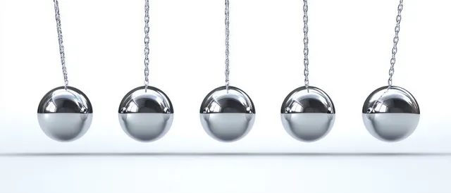 Five silver metal spheres hang from chains in an even row against a plain white background.