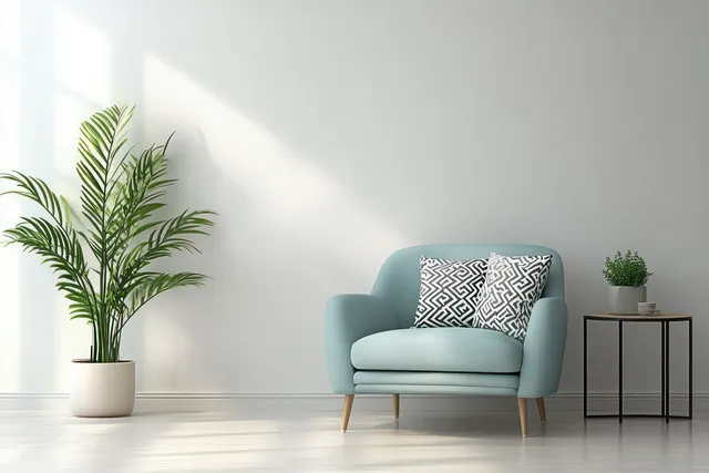 Light blue armchair with geometric cushions sits in a minimalist living room beside potted plants and a black side table.
