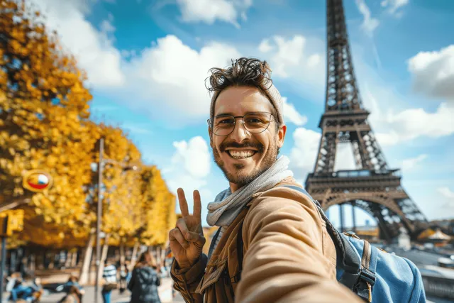 Smiling man takes a selfie in front of the Eiffel Tower in sunny Paris