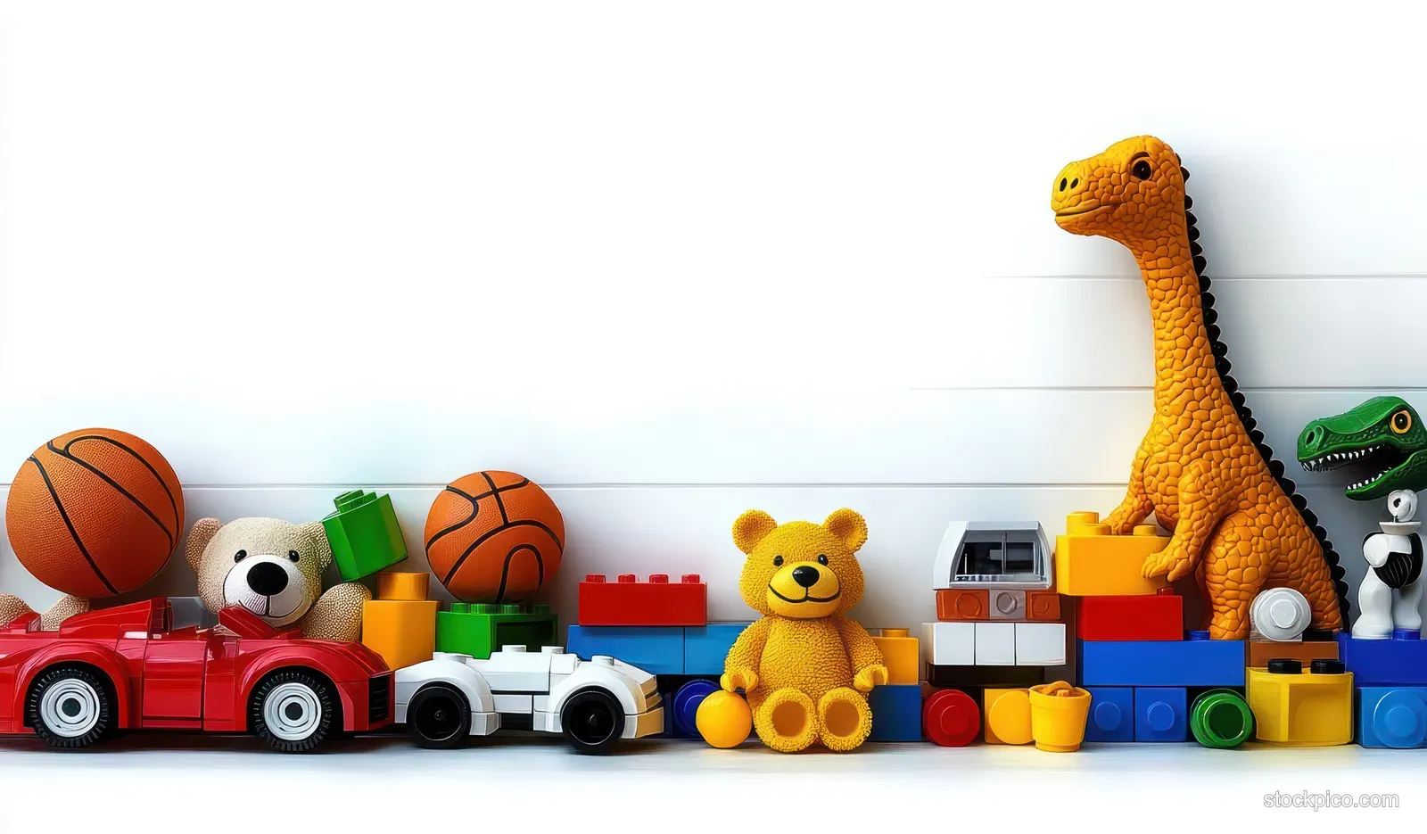 Colorful children’s toys including a yellow dinosaur, teddy bear, toy cars, balls, and building blocks on a white background.