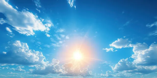 Bright sunburst shines through scattered clouds over a calm horizon in a vibrant blue sky.