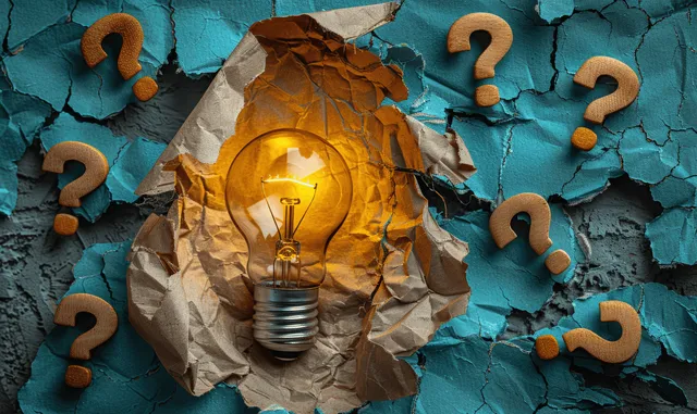Glowing lightbulb emerging from torn paper with scattered question marks on a cracked blue background.