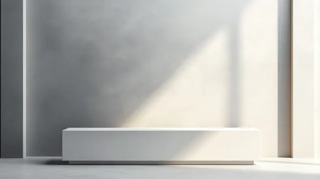 A minimalist white exhibition counter stands on a gray backdrop with a sharp shadow and clean front edge.