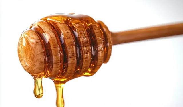 Close-Up Wooden Honey Dipper with Slow Golden Honey Drip on White Background