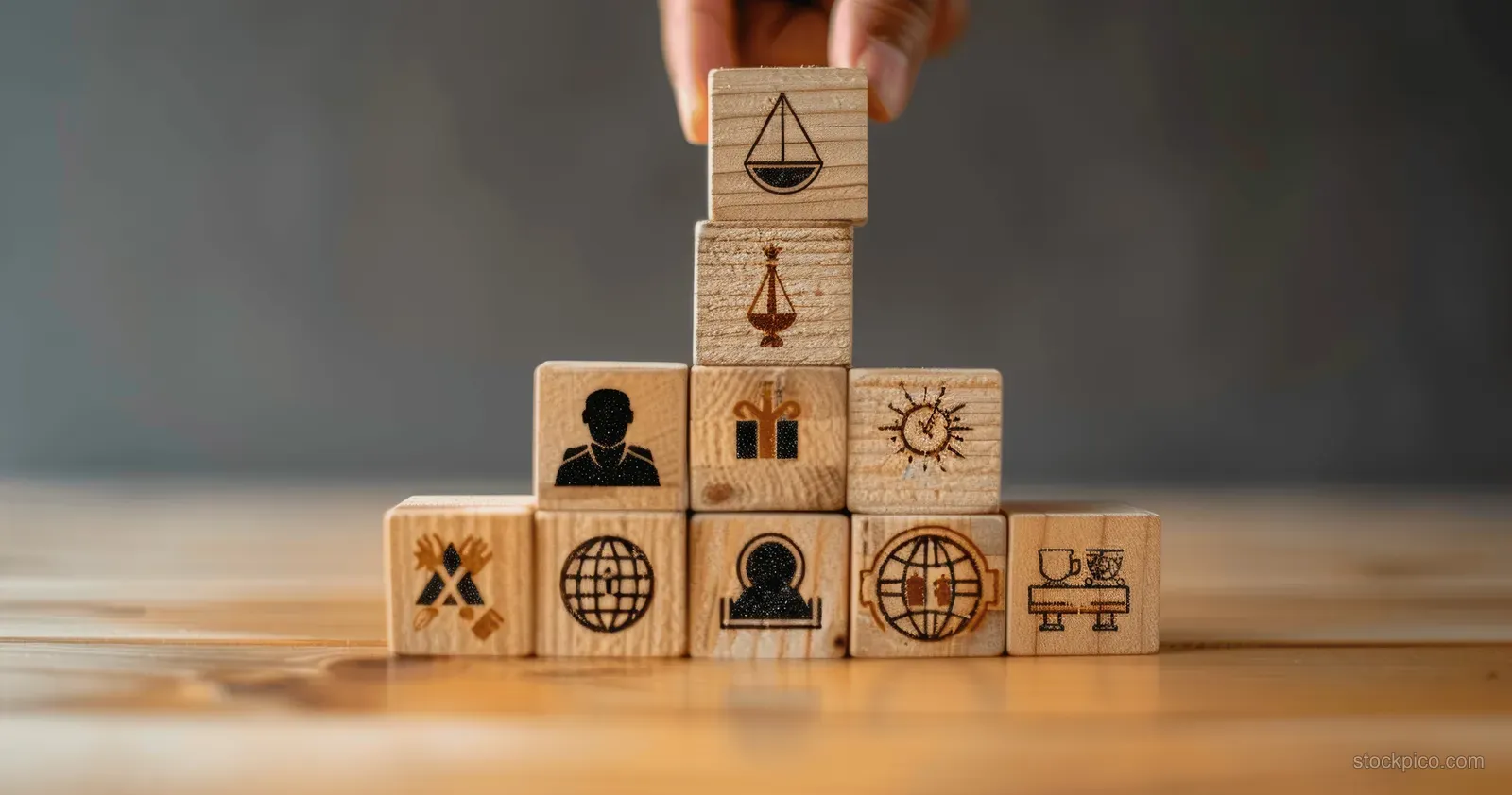 A hand places a balance scale block on a tower of governance and sustainability icons.