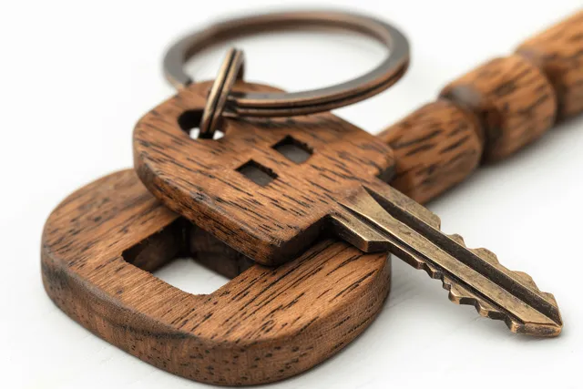 Wooden house keychain with mini house charm and keys on clean white background