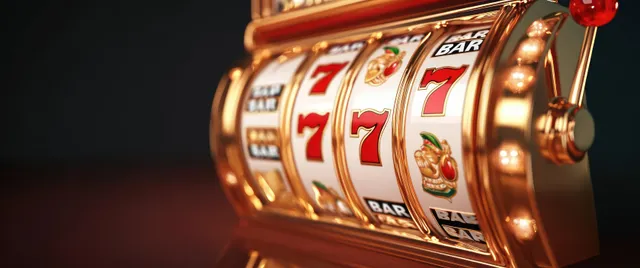 Close-up of a vintage gold slot machine showing red 7s and a roulette dial with card themed details.