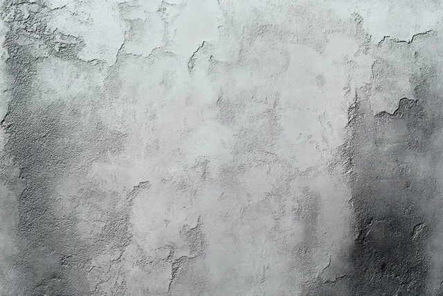Rough concrete wall close-up with peeling paint exposing layered gray and white wear.