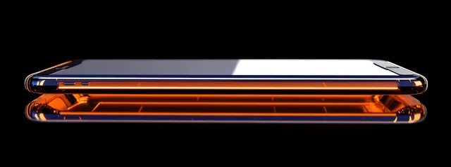 A sleek smartphone in side profile reflects vivid orange light on a glossy black surface.