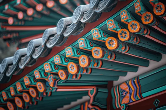 Close-up of a Korean temple roof eave with colorful carved patterns and painted wooden brackets.