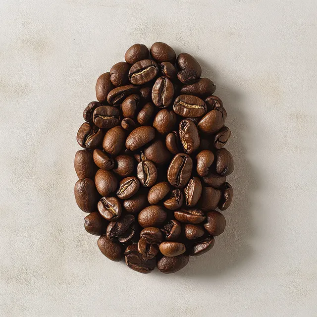 Dark roasted coffee beans are arranged in an oval on a light textured surface.