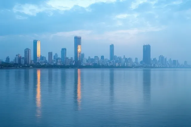 Skyscrapers stand at dawn, reflecting golden window lights on calm water under a blue cloudy sky.