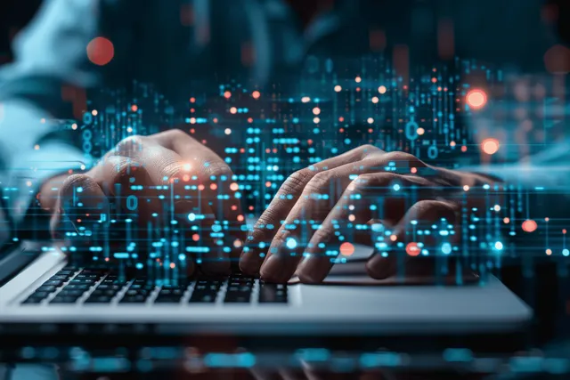 A person’s hands type on a laptop while blue network nodes and security graphics overlay the background.