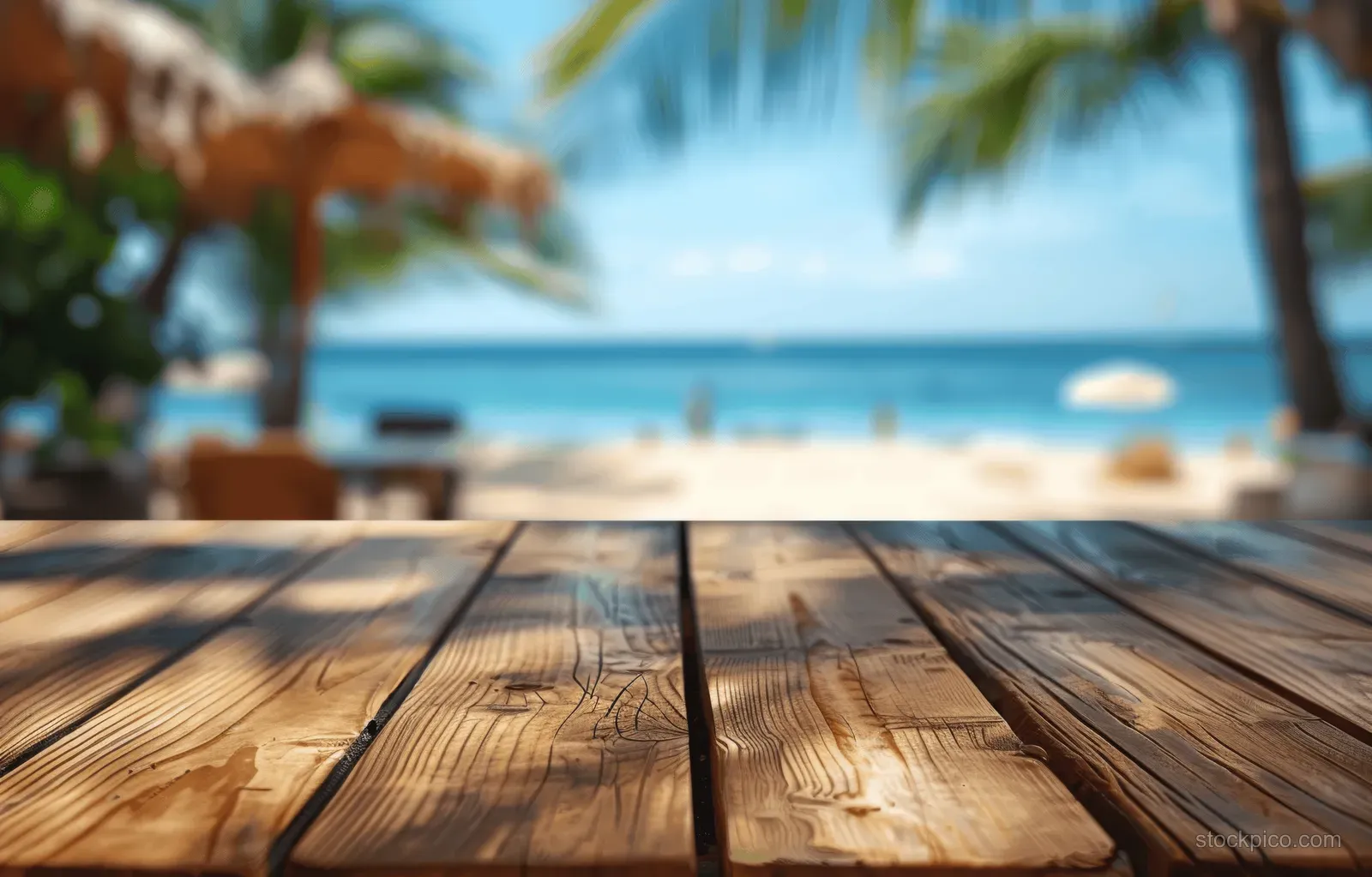 Rustic wooden table foreground with blurred palm trees and calm ocean in the tropical beach background.