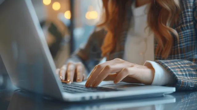 Businesswoman typing on laptop at desk, office lighting bokeh, close-up hands