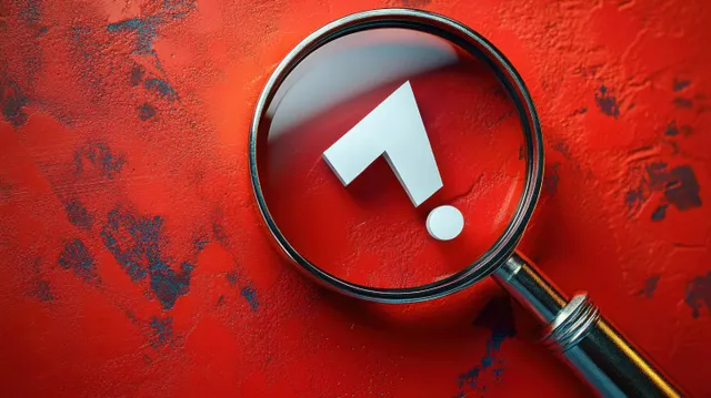 Magnifying glass enlarging a white question mark on a textured red background.
