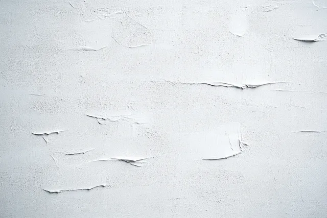 White wall paint is peeling and cracked, showing rough flaking texture across the surface.