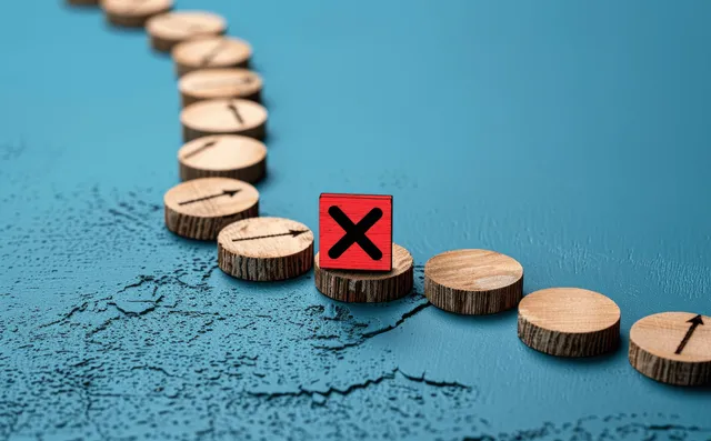 Wooden blocks form a curved arrow path on blue ground ending at a red X marked block.