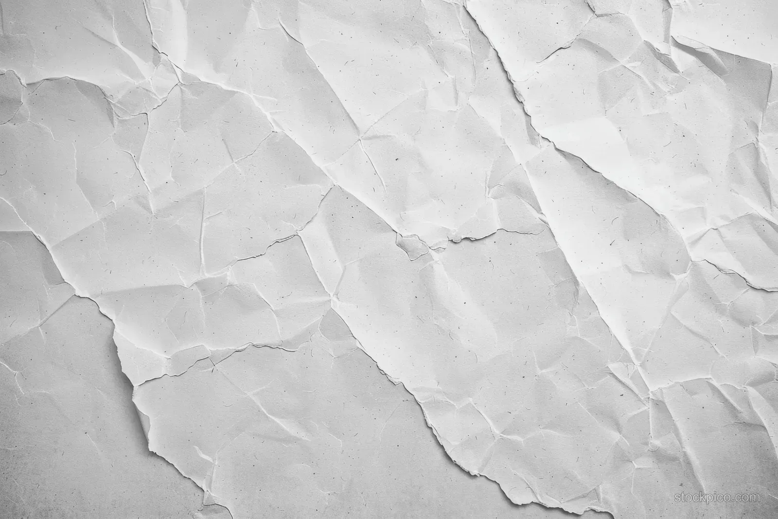 White cracked concrete wall close-up showing crumpled plaster texture with grey mottling.