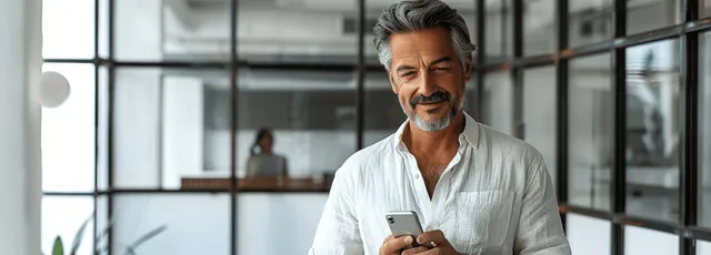 Smiling businessman using a smartphone in a bright modern office atrium