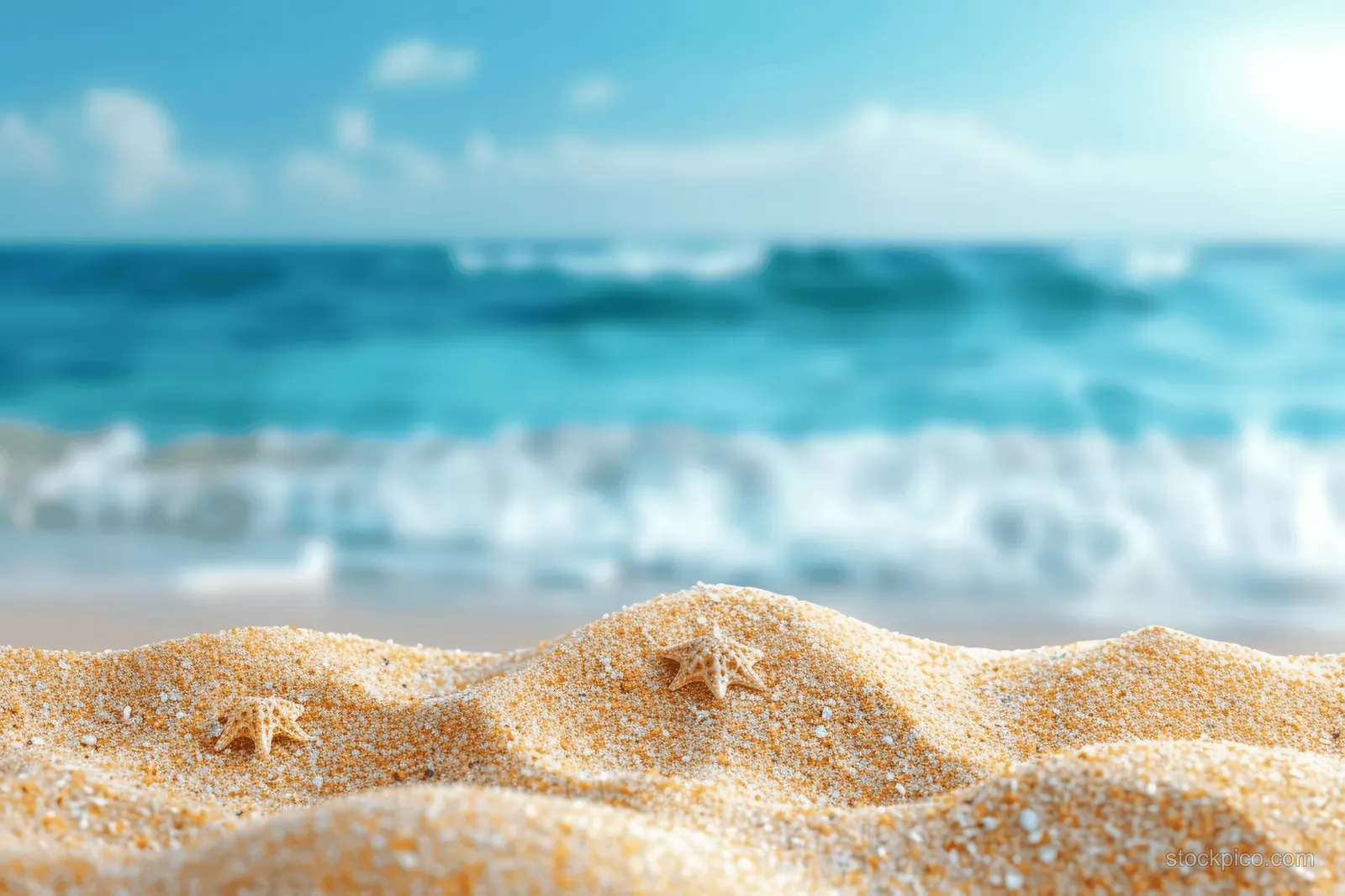 Starfish on golden sand with blue ocean waves and clear sky in the distance.