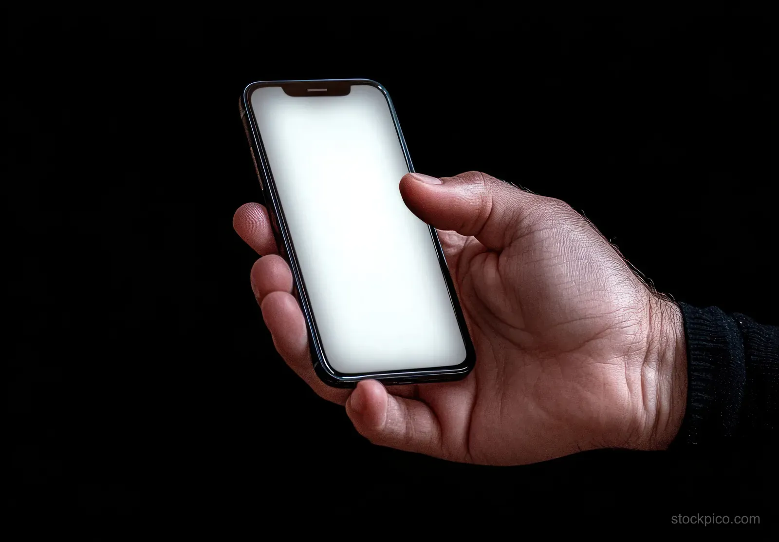 A hand holds a smartphone with a blank white screen against a black background.