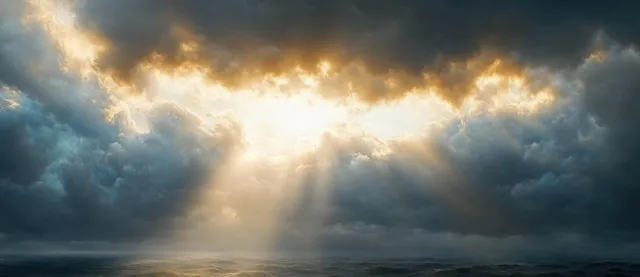 Sun rays break through dark storm clouds above a turbulent ocean with crashing wave crests.