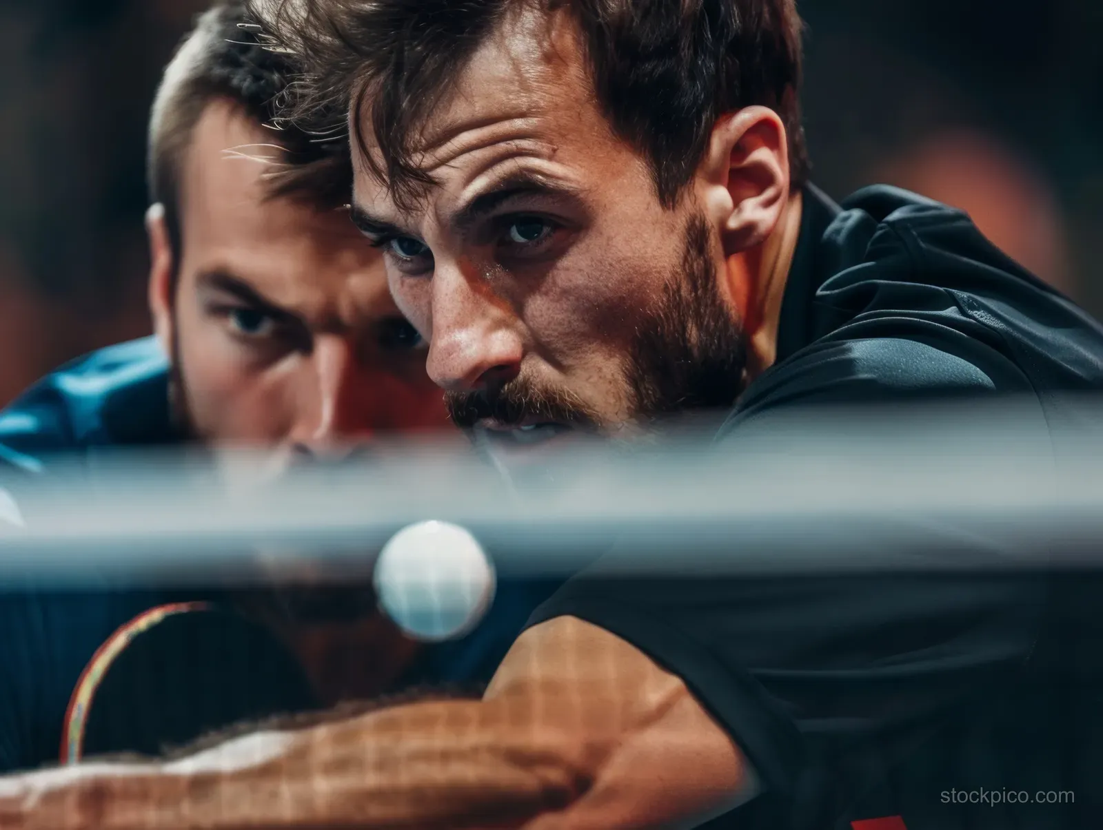 Close-up of two German doubles table tennis players leaning forward with paddles during an intense rally.