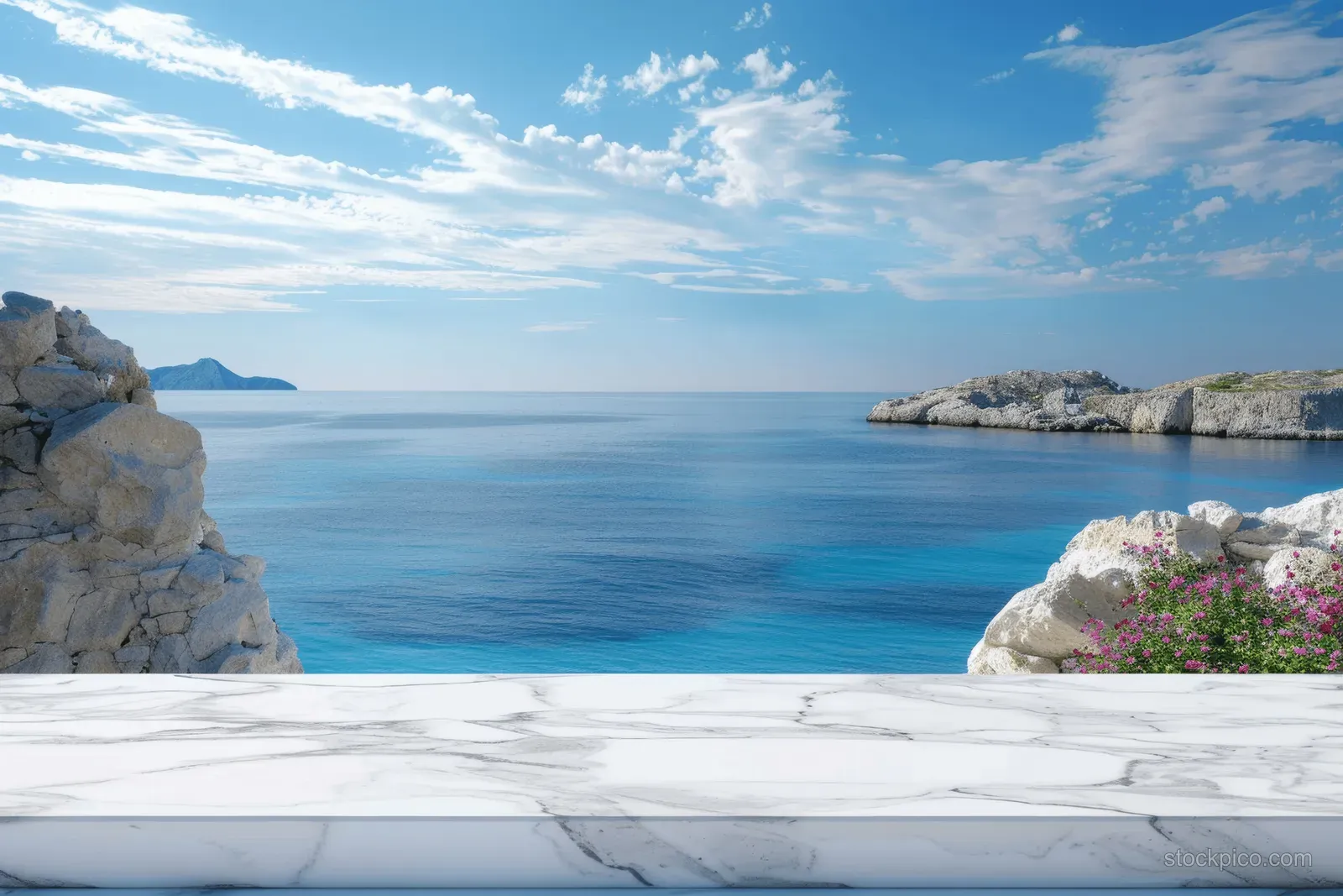 White marble table surface in front of a bright blue ocean view with rocky shoreline and soft waves.