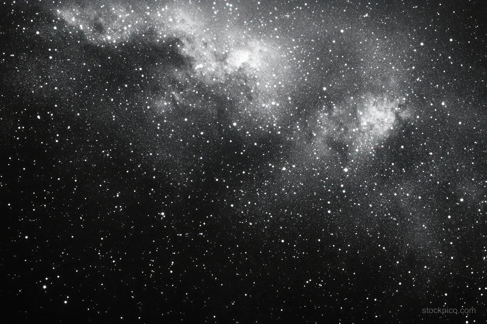Black and white star field fills the sky with dense star clusters and cloudy nebula shapes in deep space.