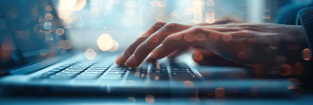 Woman’s hand typing on laptop keyboard in office light with copy space