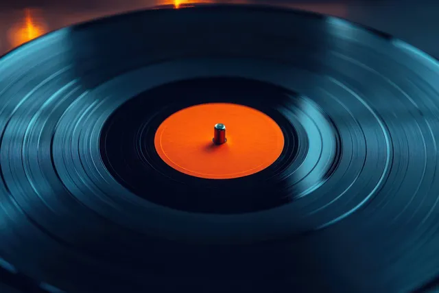 Spinning vinyl record close up on turntable with orange center label and dramatic lighting
