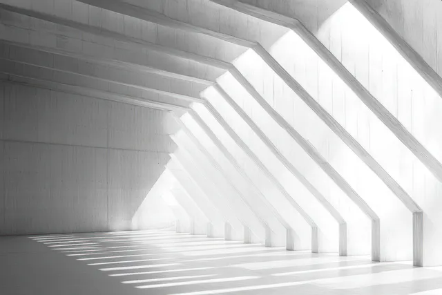 Empty concrete interior where angular beams cast sharp striped shadows on smooth floor and white walls.
