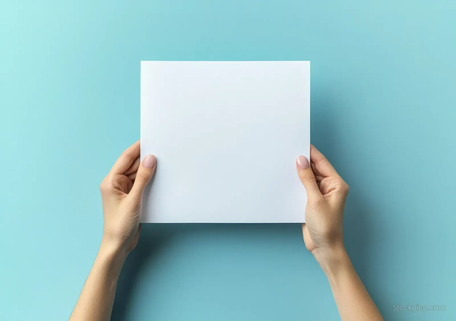 Two hands hold a blank A4 paper sheet on a bright blue background with empty copy space.