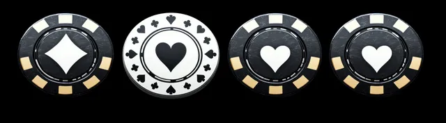 Four black and white poker chips with diamond and heart suit symbols sit on a black background.