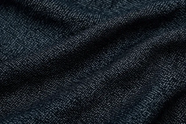 Macro close-up of dark woven fabric with thread pattern and subtle folds creating shadows.
