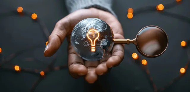 Hand holding a glowing Earth hologram with surrounding network light nodes on a dark background.