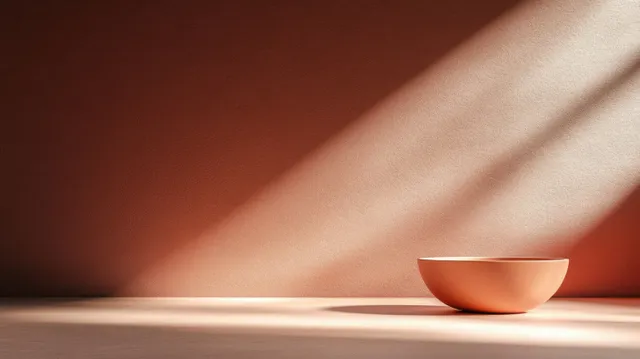 Empty terracotta bowl on smooth surface with diagonal sunlight and soft shadow detail