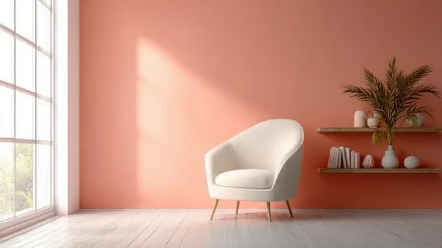 A white armchair and wall shelf sit in a minimalist living room with a peach accent wall and sunlit shadows.