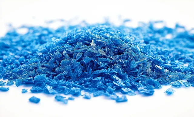 Close-up pile of shiny blue flakes scattered on white surface with metallic sparkle