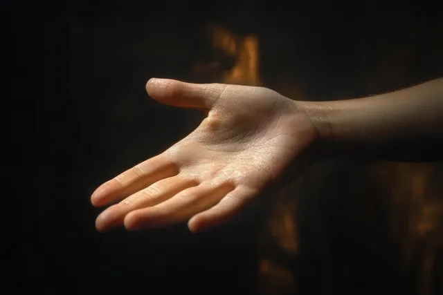 Outstretched open palm reaching toward camera with soft glow in dark blurred space