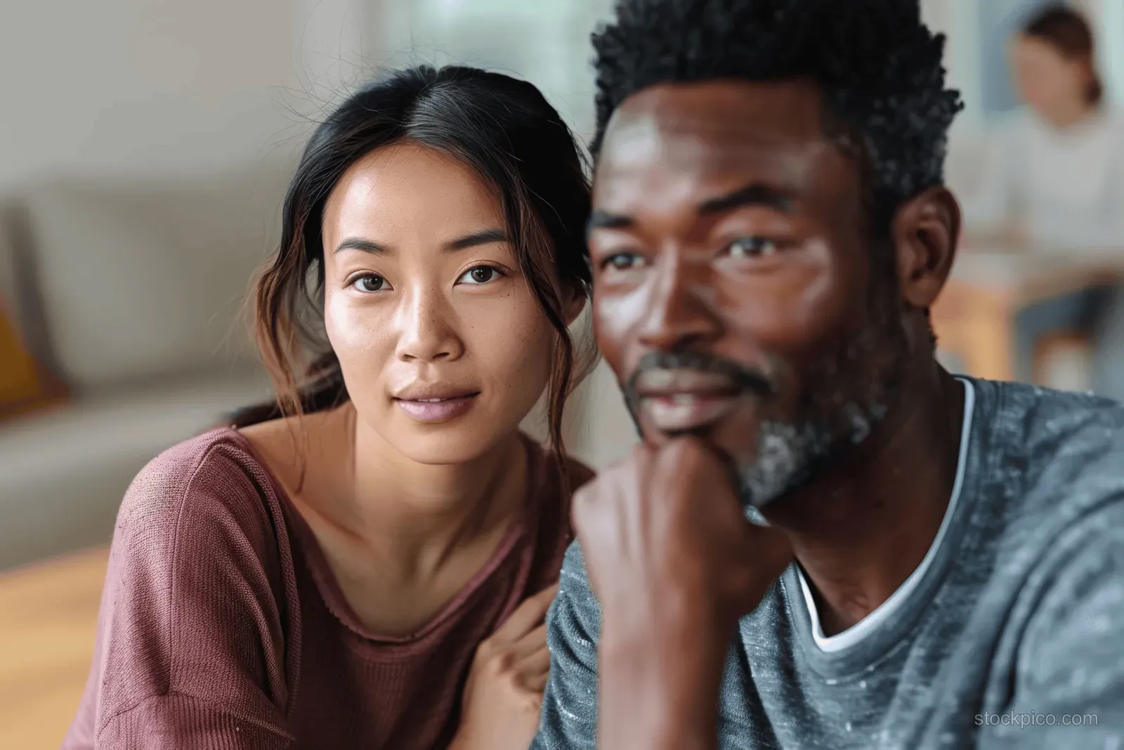 A young woman and man sit together in group therapy, looking supportive inside a community center room.