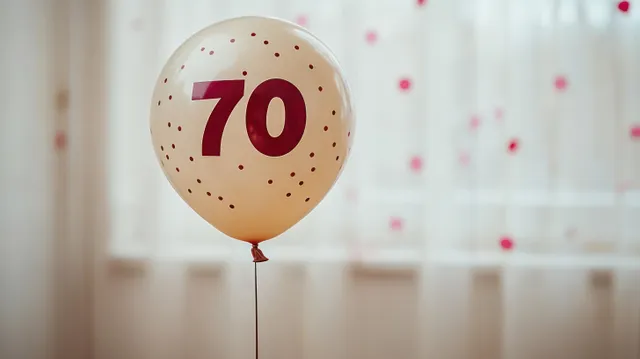 Cream balloon showing the number 70 floating indoors with a blurred window and curtains in the background.