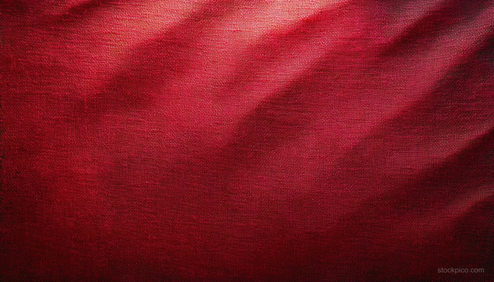 Close-up red canvas fabric texture with diagonal folds and strong shadowed lighting.
