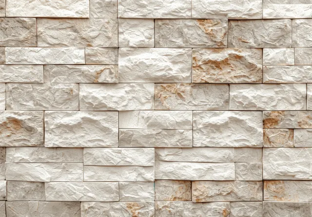 Beige and white stone brick wall texture with chipped mortar seams and uneven stone blocks.