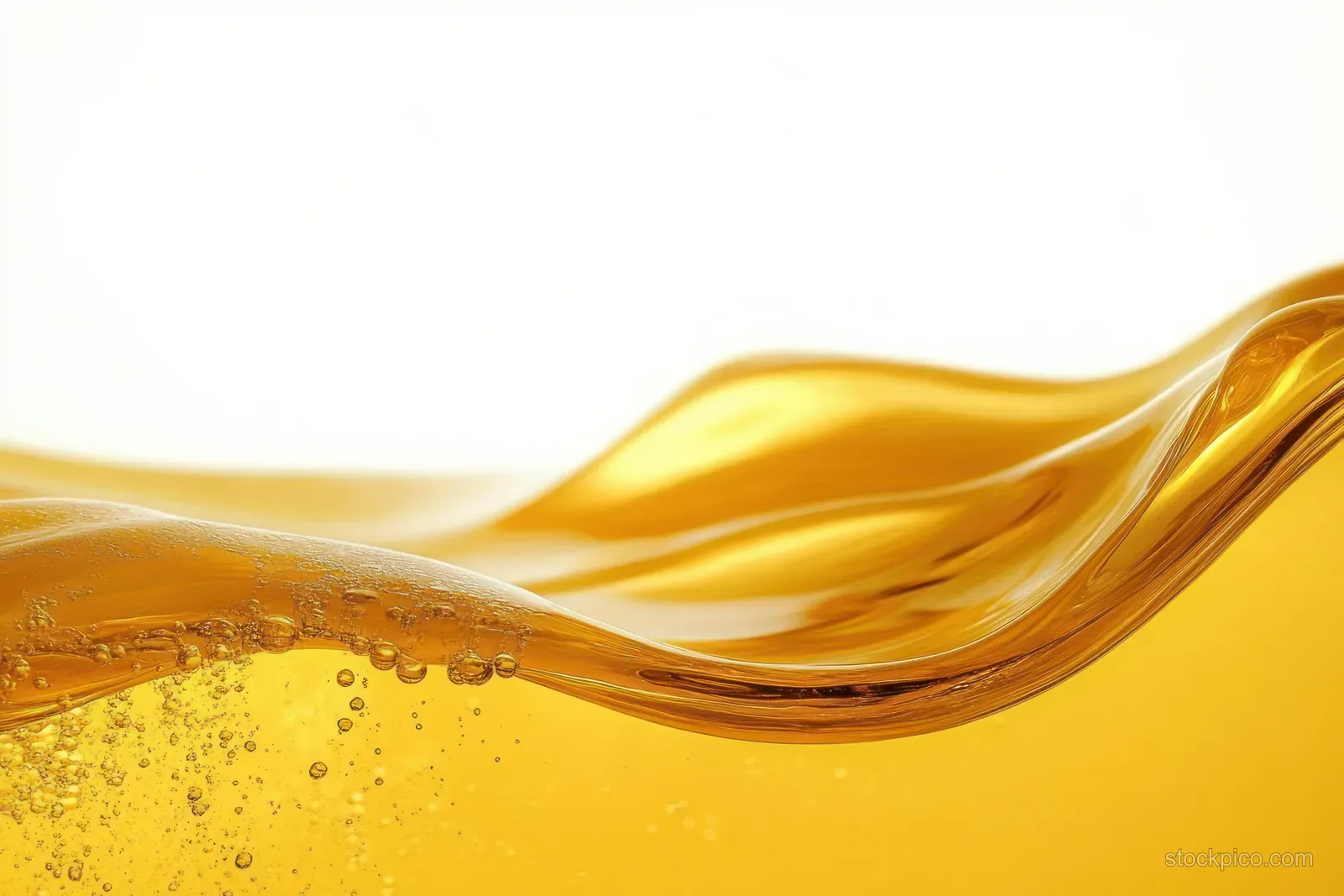 Golden translucent liquid pours in smooth waves with small bubbles and shimmering highlights.