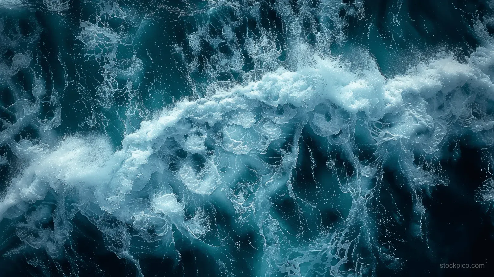 Top-down view of ocean waves with white foam over dark blue water.