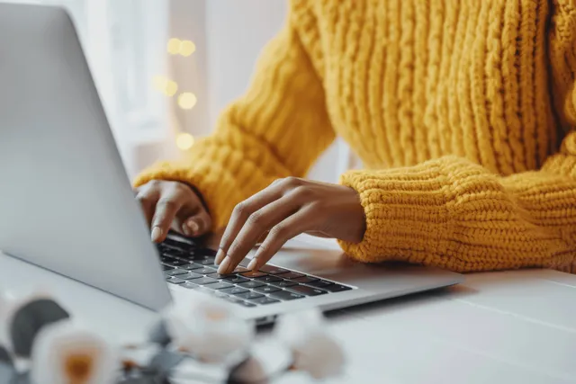 African American woman’s hands typing on laptop in bright minimalist white office